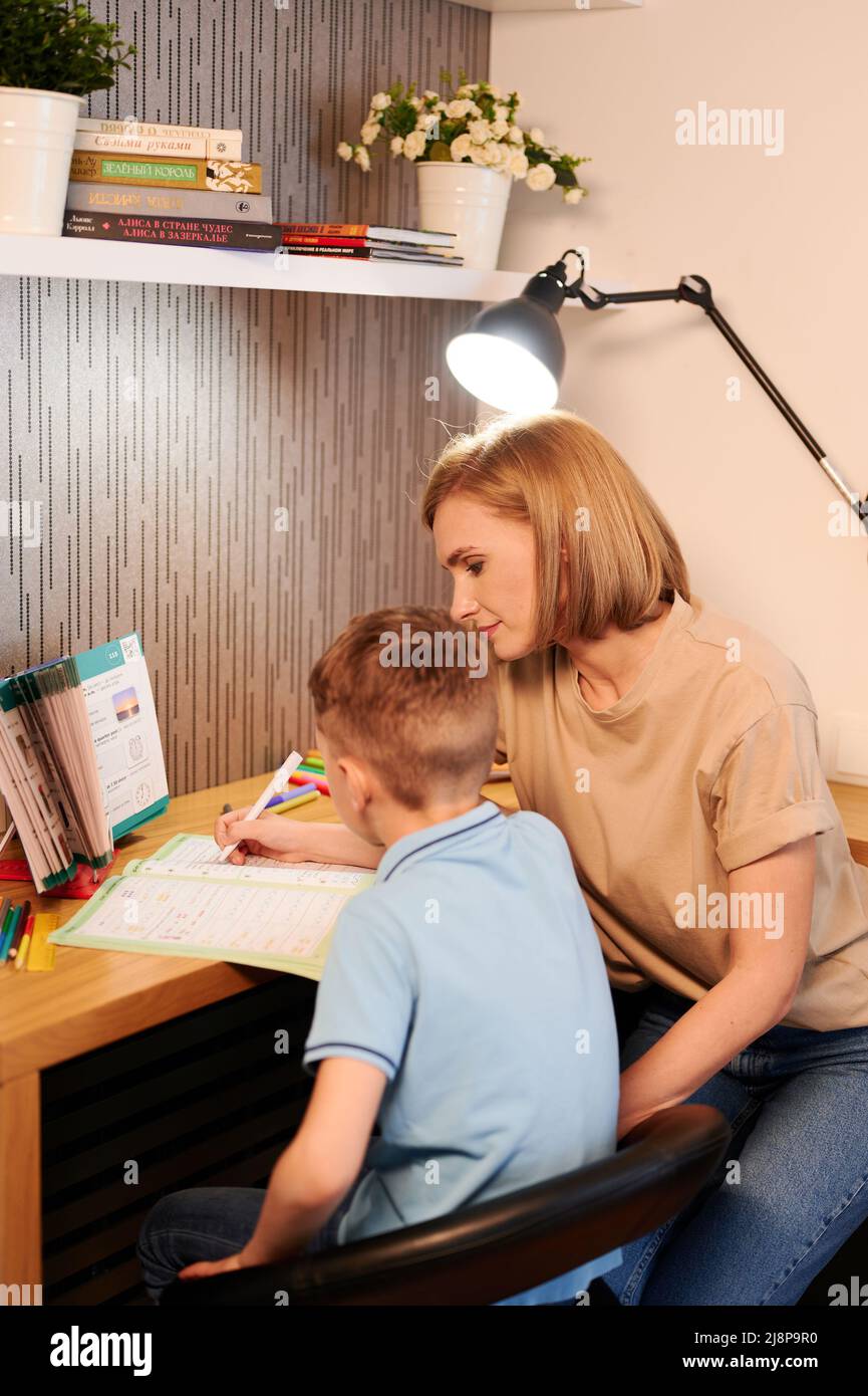 Caucasian Mother Help Son With Homework Sitting At Desk In Bedroom