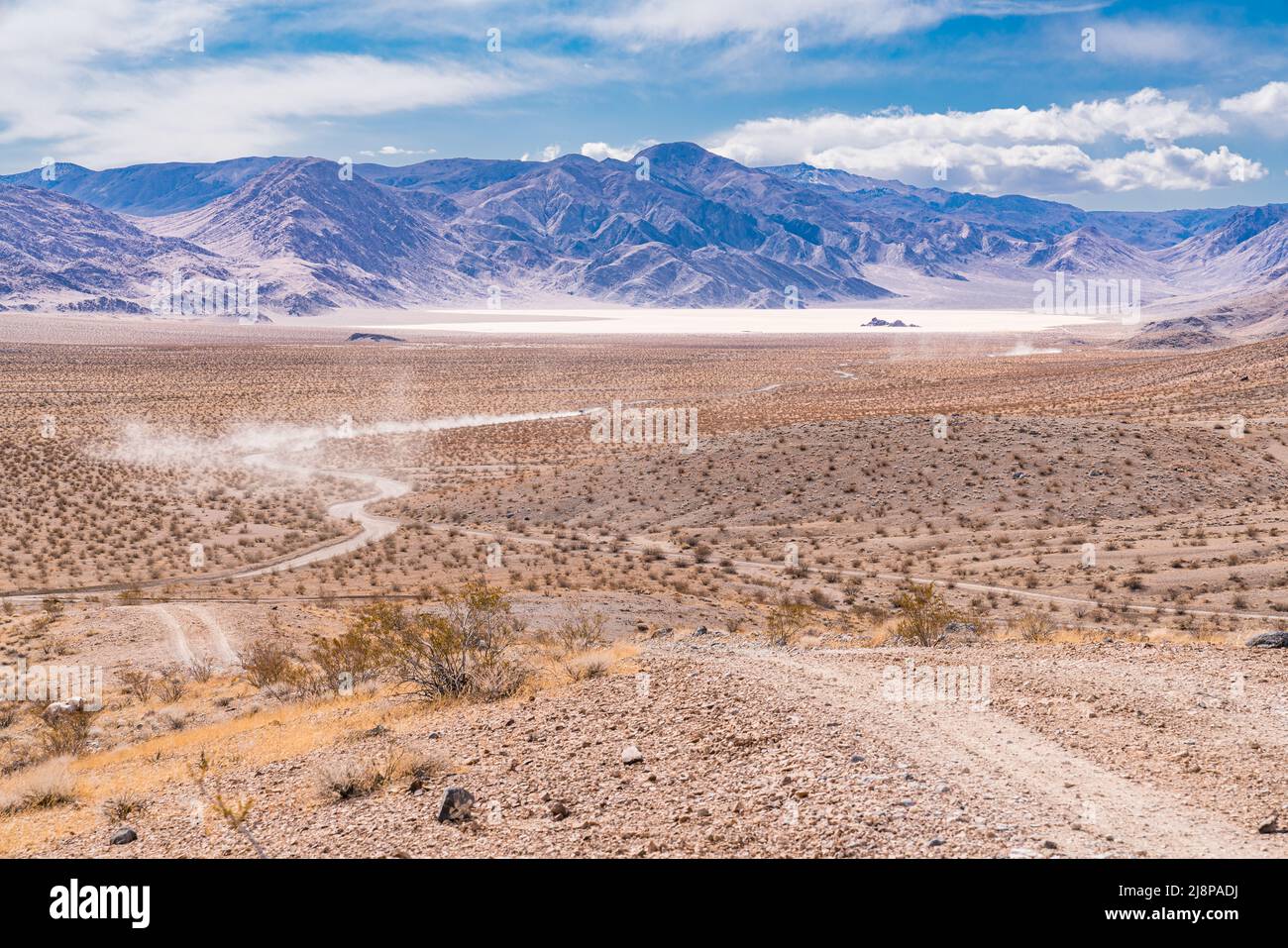Vehicles travel down the gravel road towards the Racetrack Playa in Death Valley National Park Stock Photo