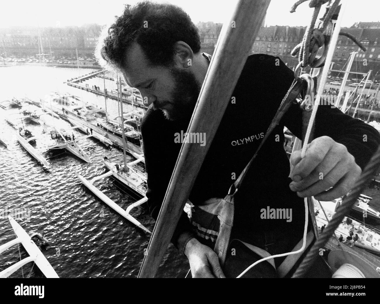 AJAXNETPHOTO. NOVEMBER, 1982.ST.MALO, FRANCE. - BRITISH SKIPPER - ROBIN KNOX JOHNSTON MAKES LAST MINUTE ADJUSTMENTS TO THE MAST OF HIS CATAMARAN OLYMPUS 3 BEFORE RACE START. PHOTO:JONATHAN EASTLAND/AJAX REF:8211 65 Stock Photo