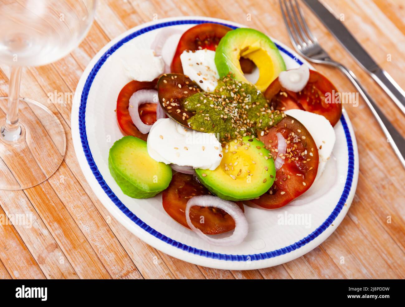 Caprese avocado salad with tomatoes, mozzarella, onion, pesto and