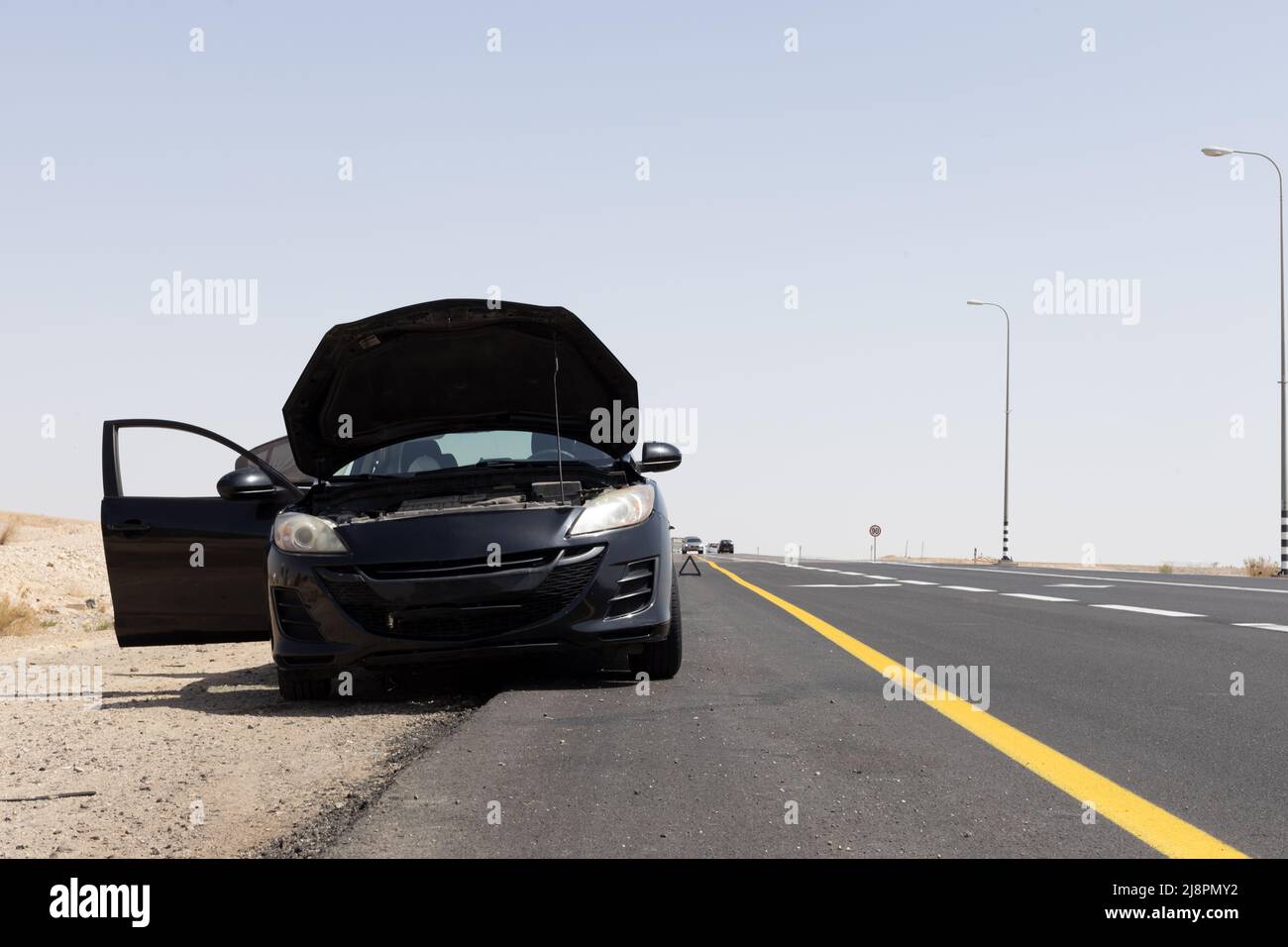 black car with open hood on the side of the road Stock Photo