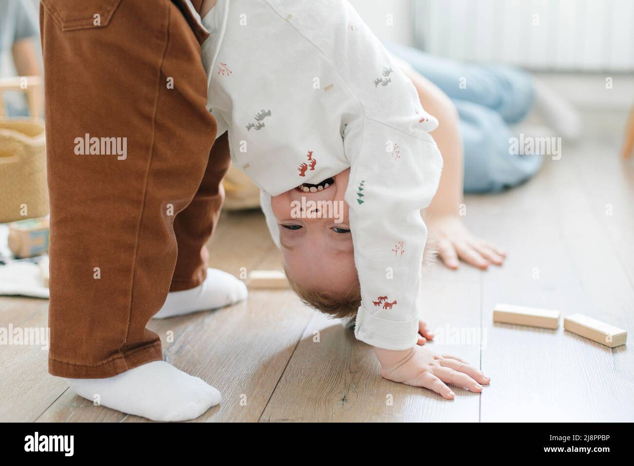 Children play on the floor of the children's room. Little brother amuses his brother and sister