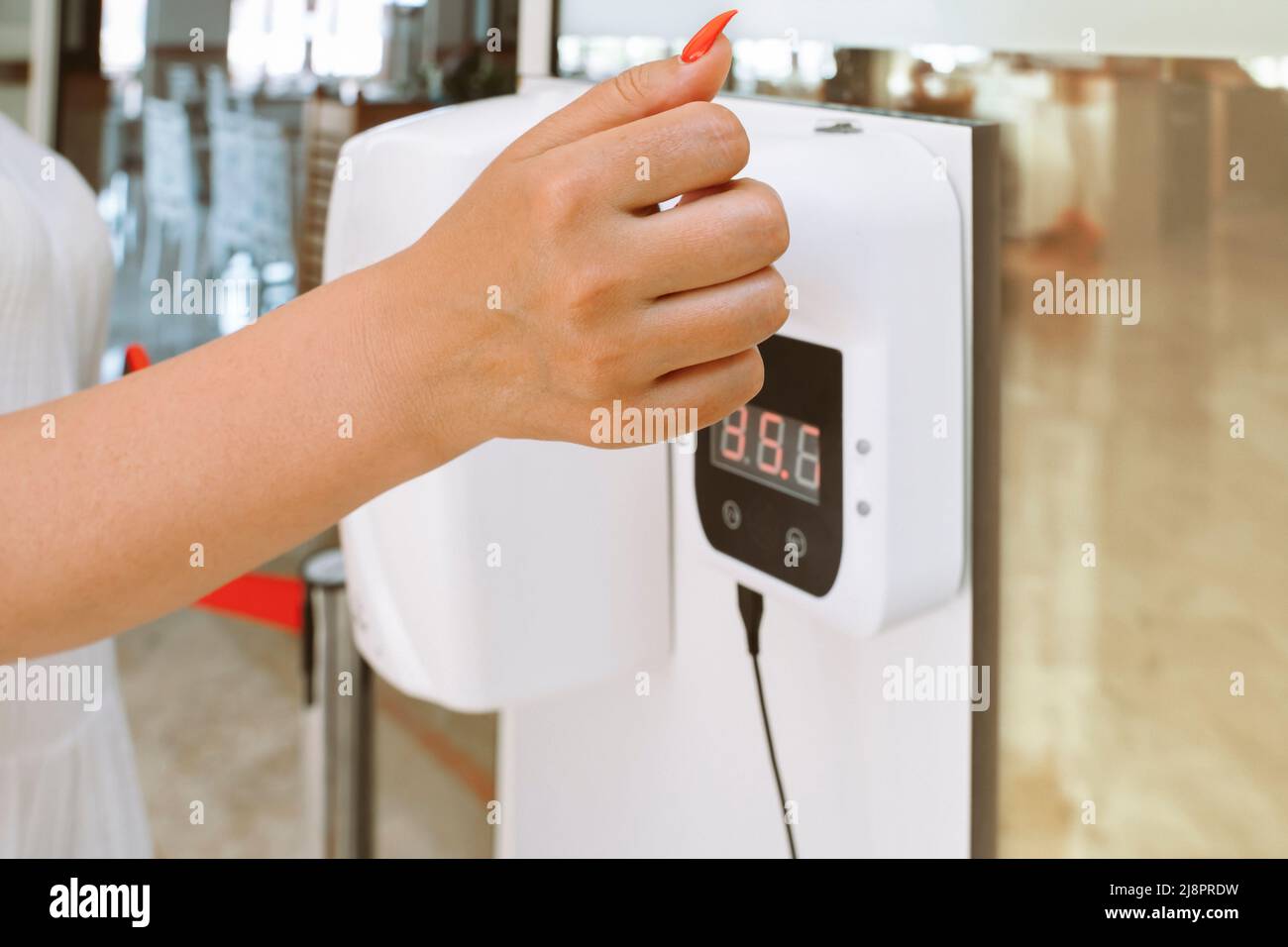 lady hand checking temperature before entering restaurant with automatic body measuring temperature check machine Stock Photo