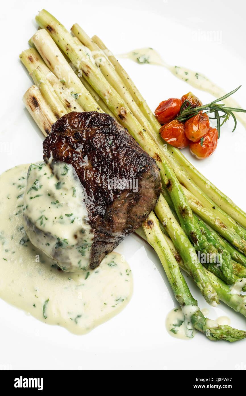 grilled filet mignon tenderloin steak with asparagus and creamy dill sauce on white background Stock Photo
