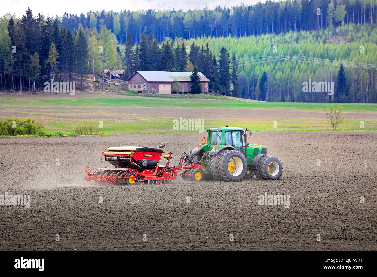 Farmer working with John Deere 6820 tractor and Väderstad Biodrill seed drill in field on a day of spring. Salo, Finland. May 15, 2021. Stock Photo