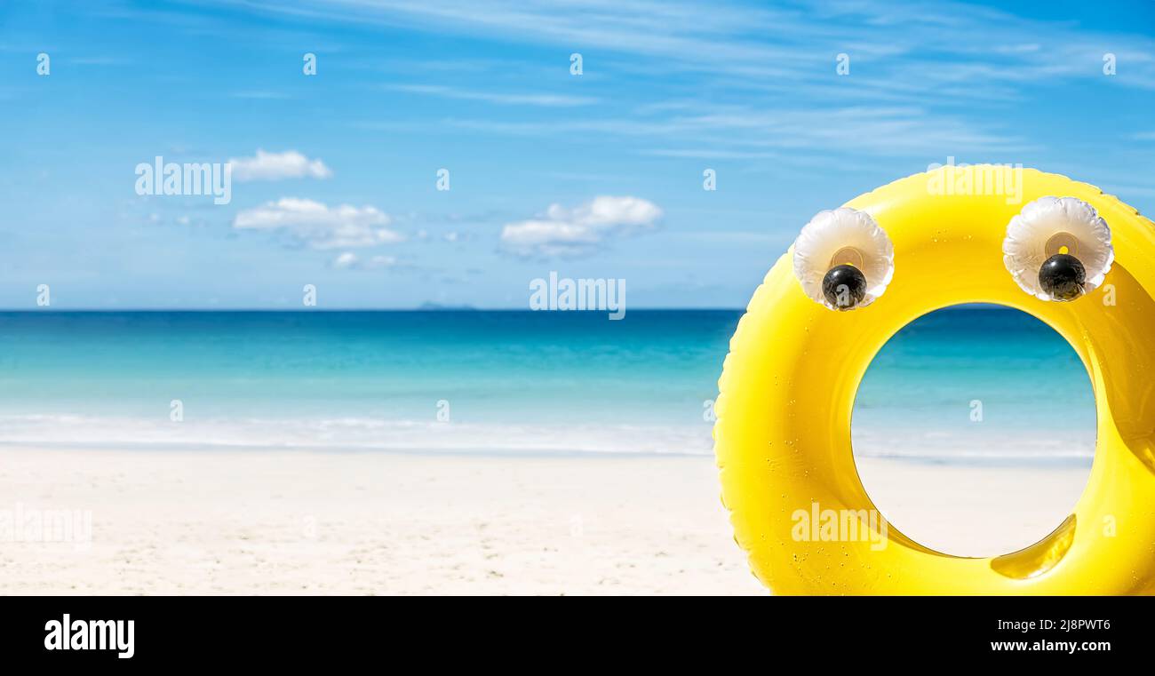 Large yellow rubber inflatable ring on sea side background at sunny day, tropical summer holiday concept Stock Photo