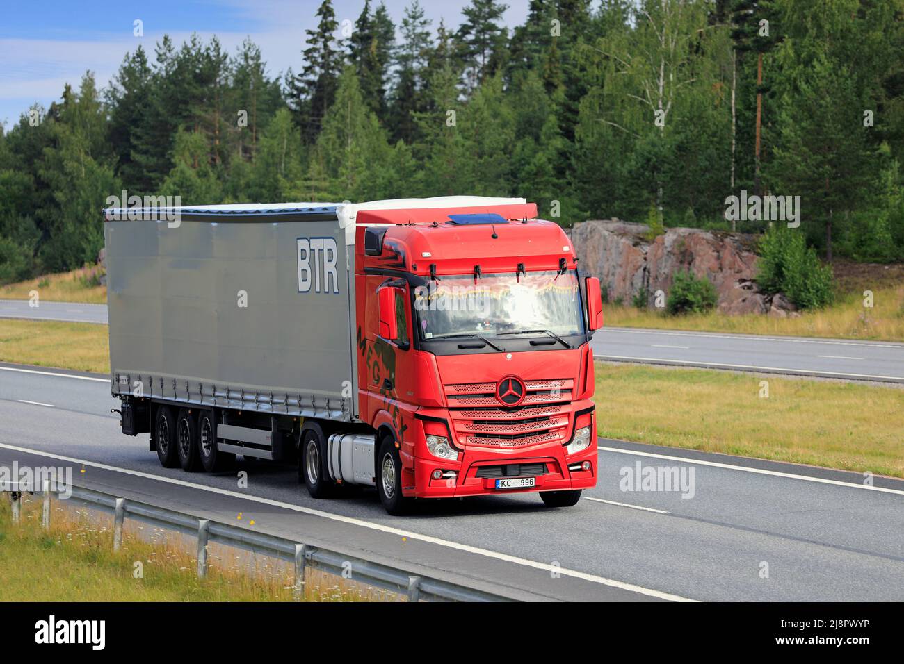 Red Mercedes-Benz Actros truck Megatex in front of semi trailer at speed on motorway on a day of summer. Salo, Finland. July 9, 2021. Stock Photo