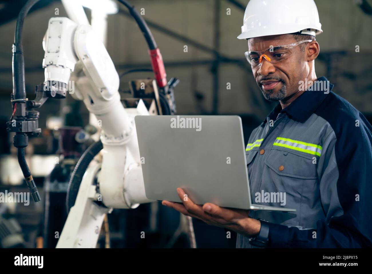 African American factory worker working with adept robotic arm in a