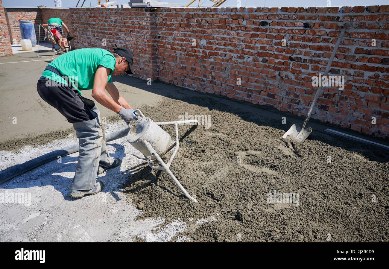 Male worker using concrete screed mixer machine while preparing sand