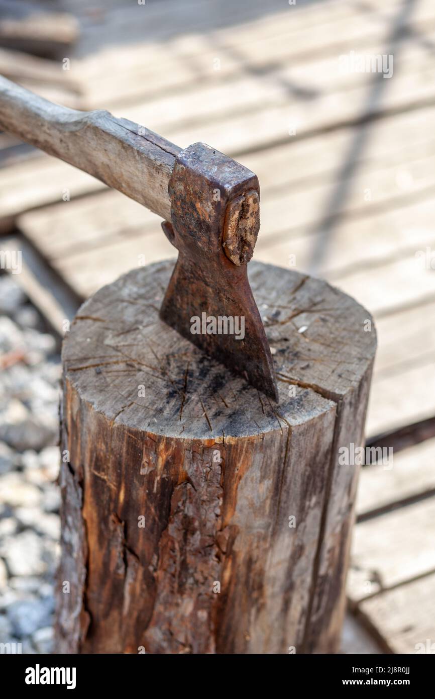 Village life. An axe in a stump or log for chopping firewood. The wood chopper sticks out in wooden hemp. Deforestation by a sharp axe. Rusty but very Stock Photo