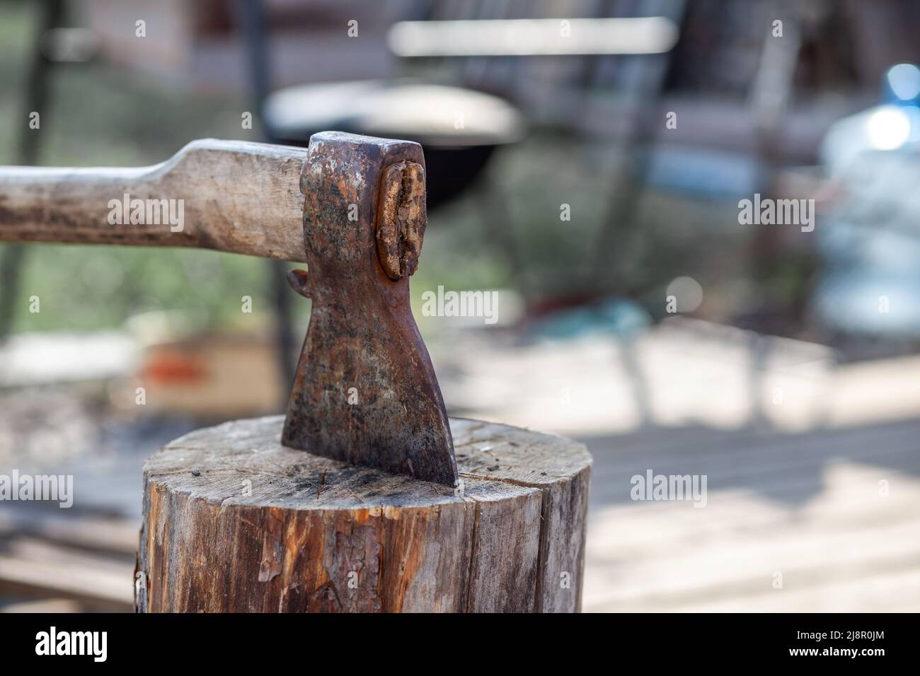 Village life. An axe in a stump or log for chopping firewood. The wood chopper sticks out in wooden hemp. Deforestation by a sharp axe. Rusty but very Stock Photo