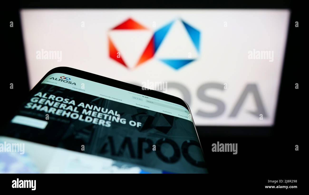 Mobile phone with webpage of Russian diamond mining company Alrosa PJSC on screen in front of business logo. Focus on top-left of phone display. Stock Photo