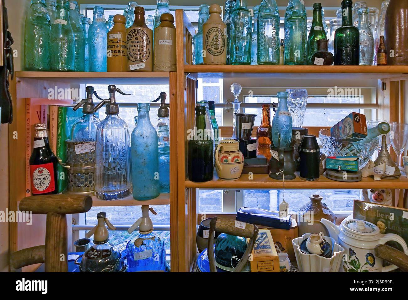 Assortment of old vintage glass bottles and containers on display on shelves in antique shop window, Uppingham, England, UK Stock Photo