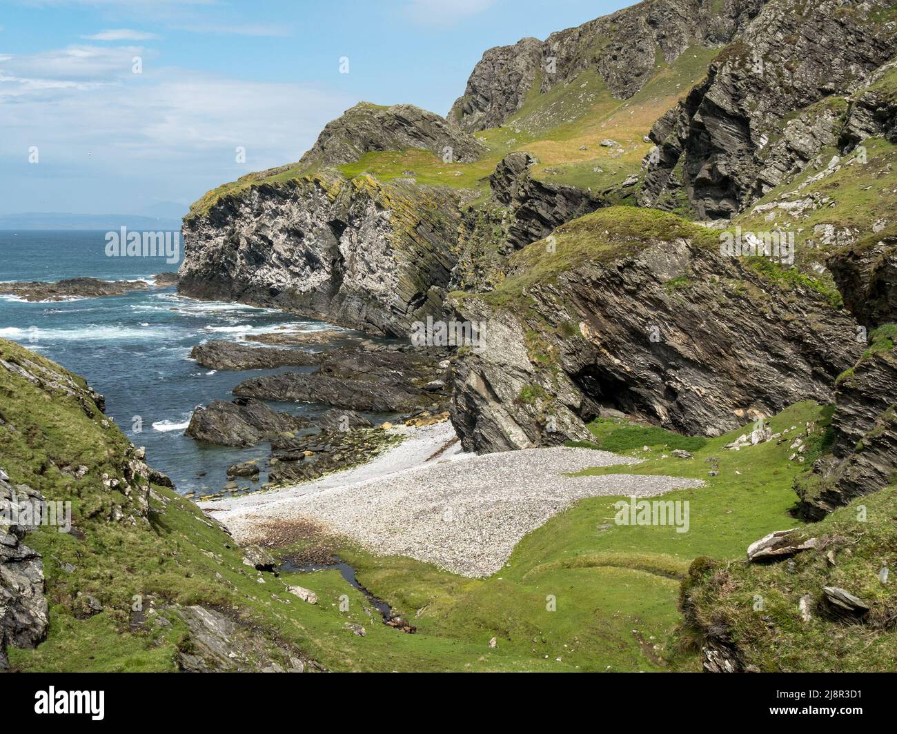 Sea cliffs and pebble beach at Port Ban near Pigs Paradise on the Hebridean Island of Colonsay, Scotland, UK Stock Photo