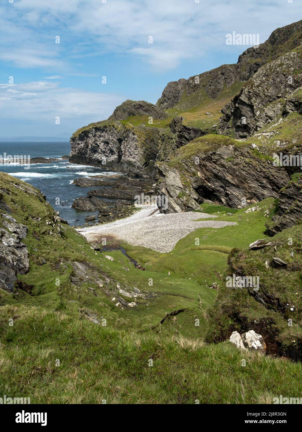 Sea cliffs and pebble beach at Port Ban near Pigs Paradise on the Hebridean Island of Colonsay, Scotland, UK Stock Photo