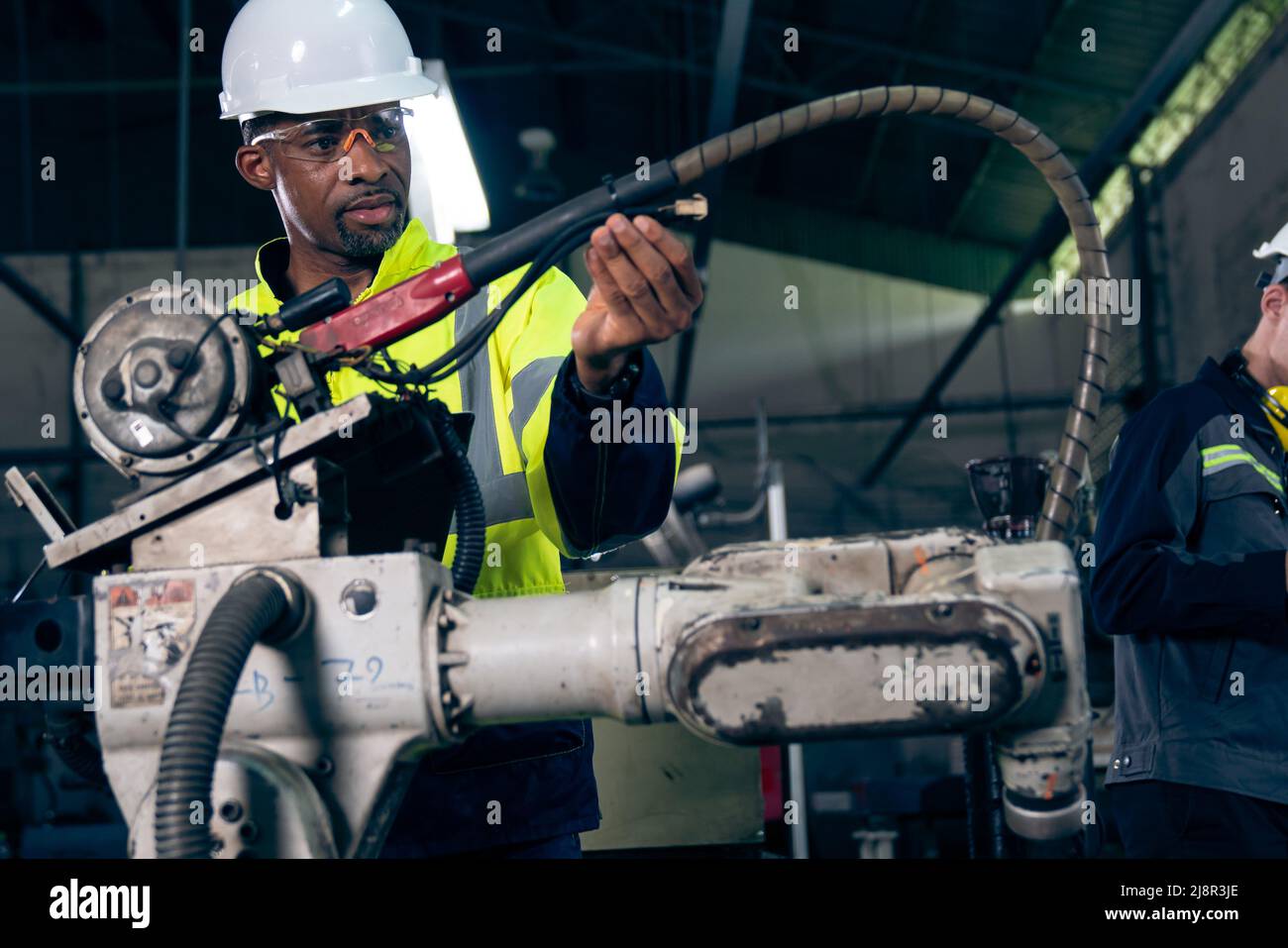 African American factory worker working with adept robotic arm in a