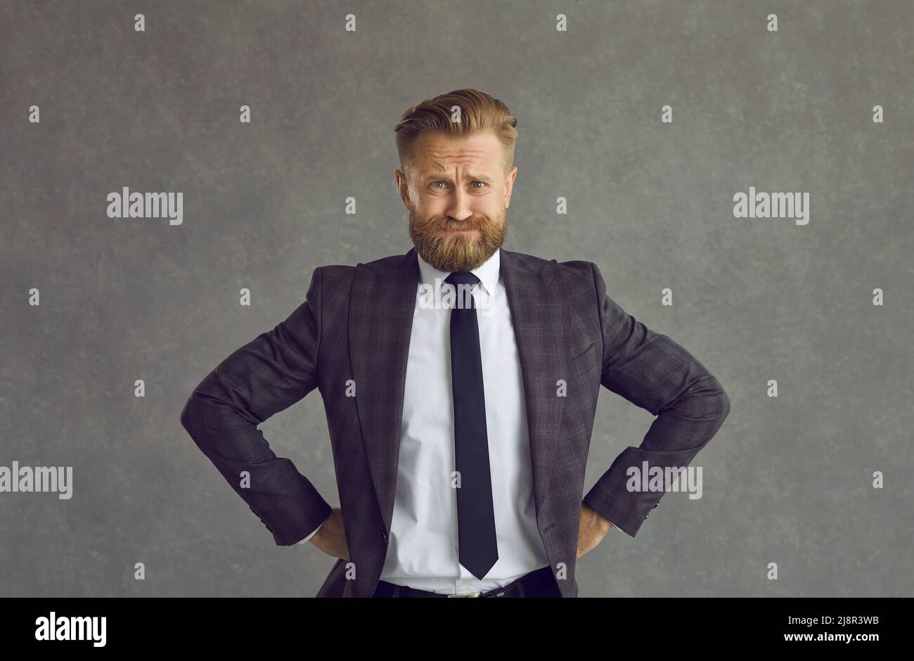 Anxious and tense businessman expecting something while standing on a gray background. Stock Photo
