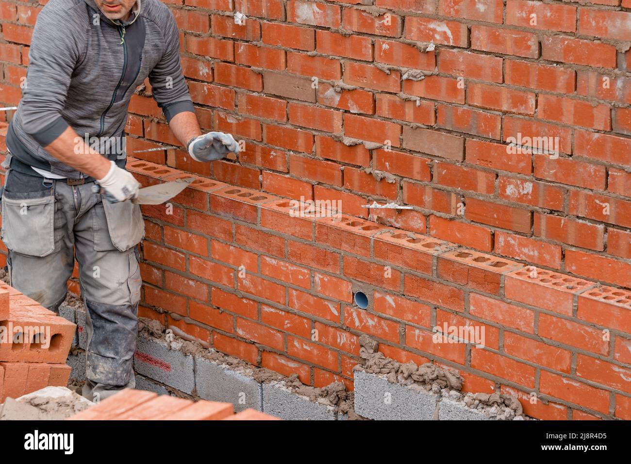 Bricklayer laying bricks on mortar on new residential house