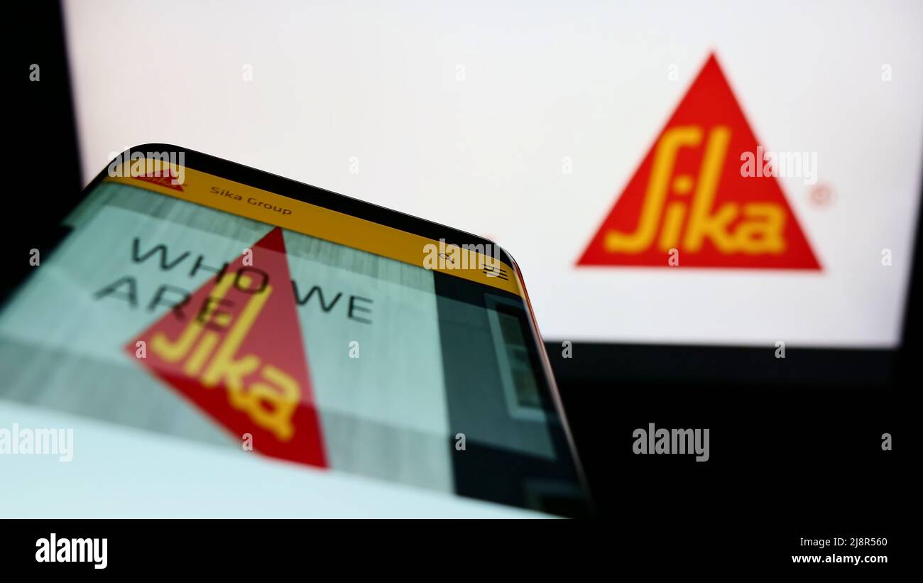 Smartphone with website of Swiss specialty chemicals company Sika AG on screen in front of business logo. Focus on top-left of phone display. Stock Photo