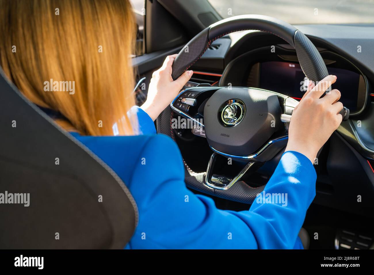 Back view of woman driving Skoda car in blue suit, May 2022, Prague, Czech Republic Stock Photo