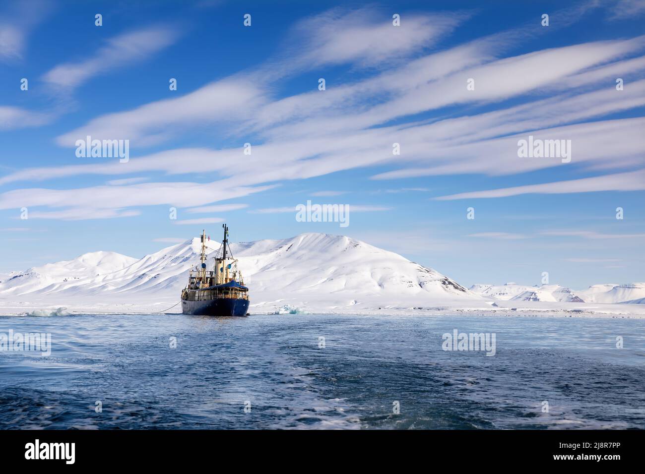 Icebreaker at anchor in the arctic waters of Svalbard, a Norwegian archipelago between mainland Norway and the North Pole. Crisp blue sky and snowy mo Stock Photo