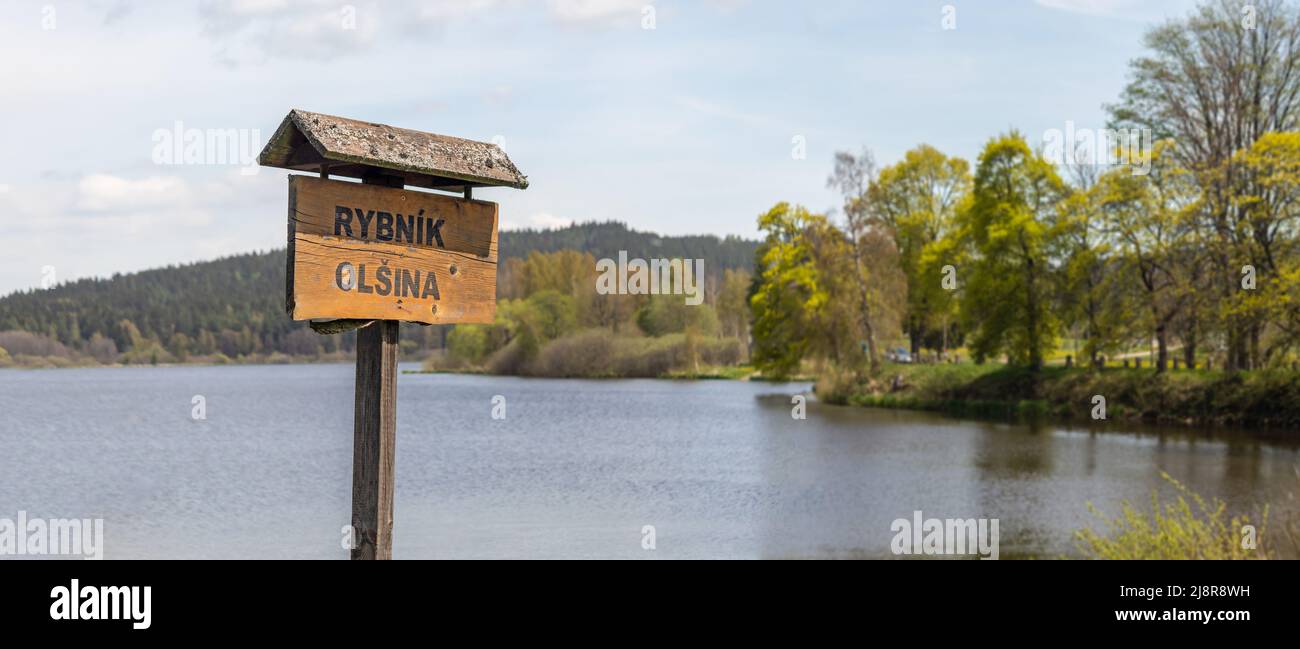 tourist signpost by the water, wooden sign with inscription Olsina Pond, Czech republic Stock Photo