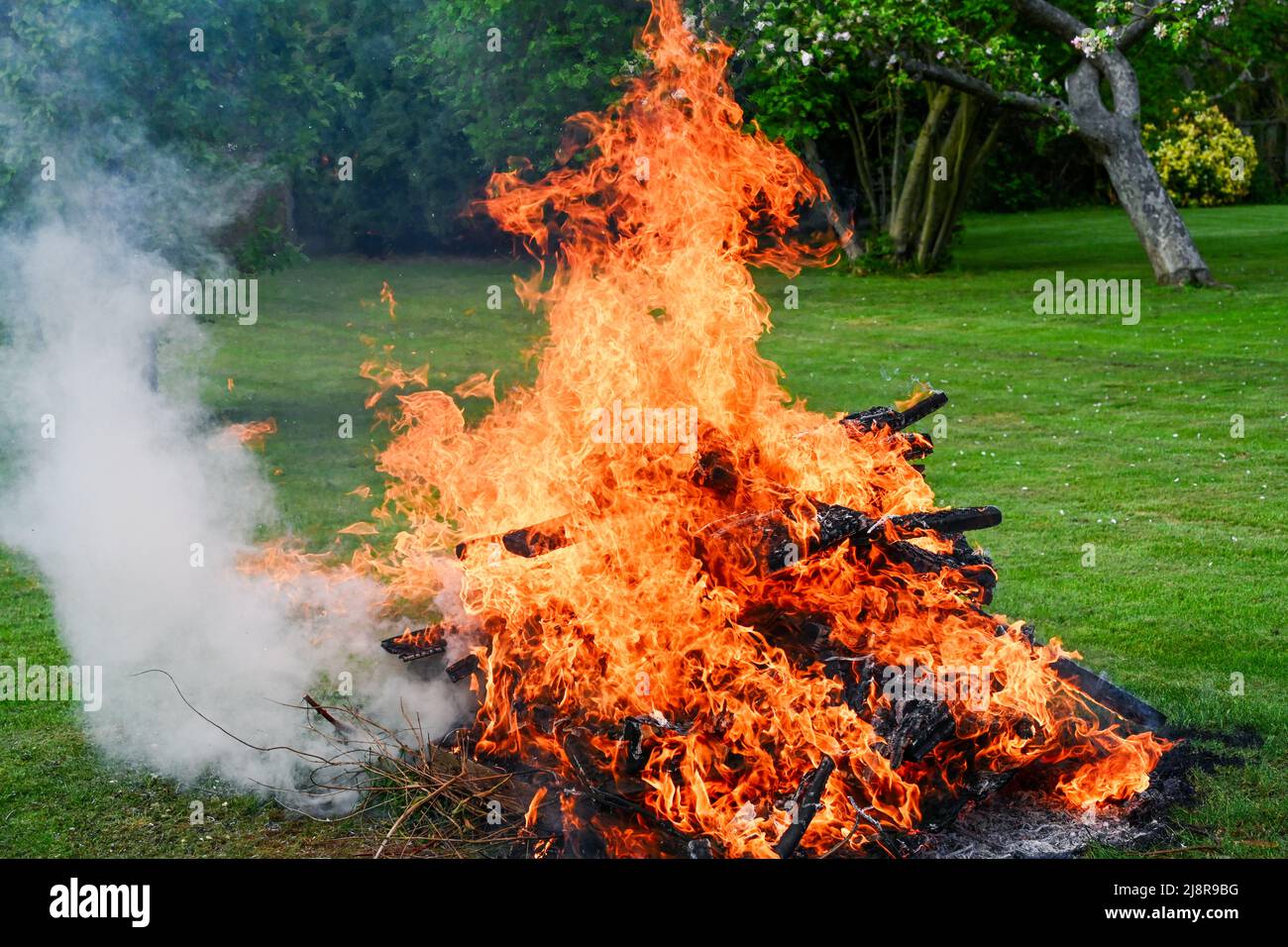 A garden bonfire with flames raging and smoke billowing out from the side Stock Photo