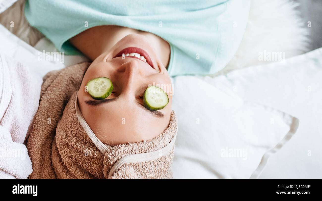 Two girls make homemade face and hair beauty masks. Cucumbers for the freshness of the skin around the eyes. Women take care of youthful skin. Girlfri Stock Photo