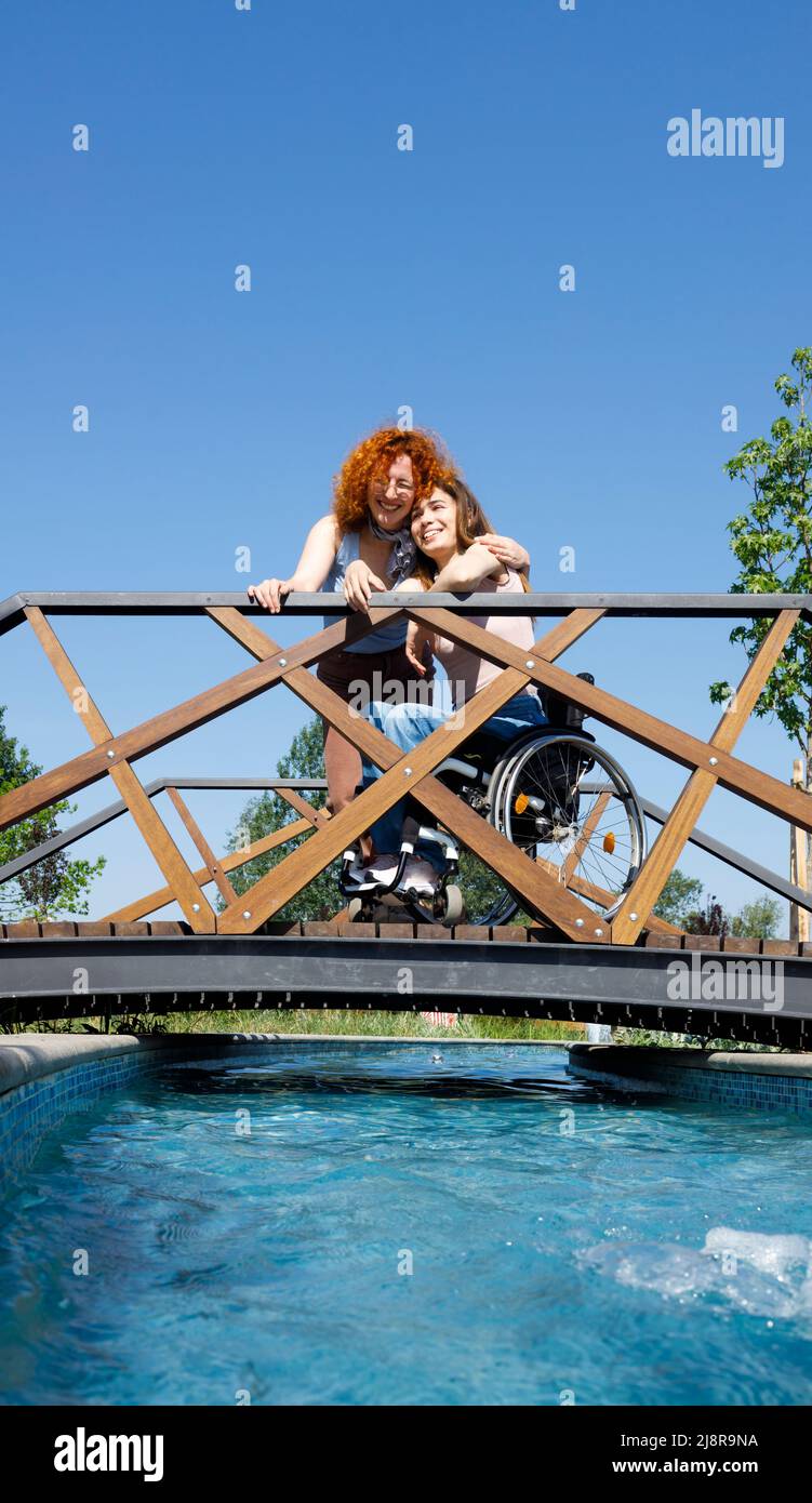 A woman hugging and supporting her disabled female friend on a clear summer day Stock Photo