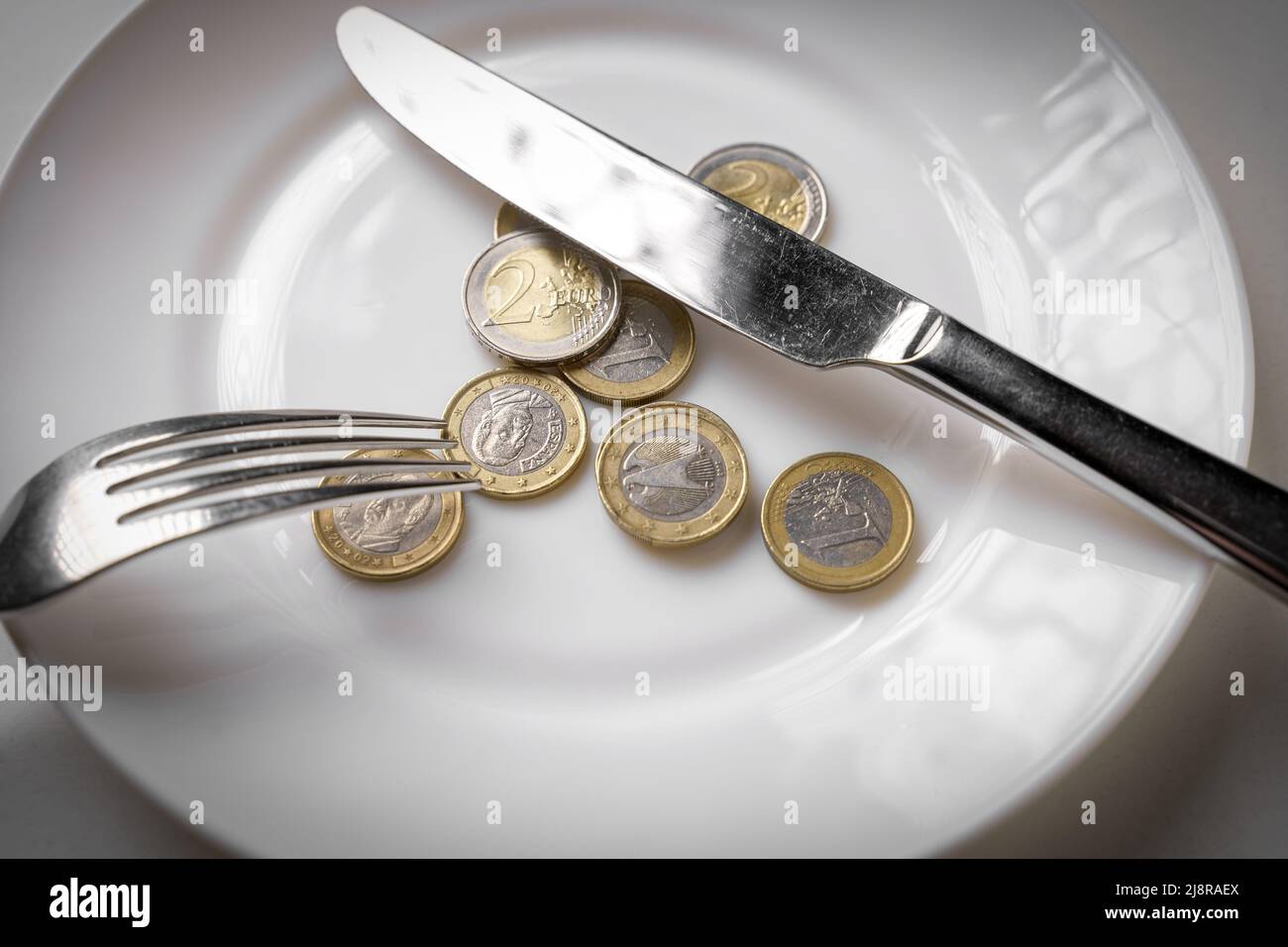 Plate of coins with a fork and knife. Money and food concept Stock Photo -  Alamy