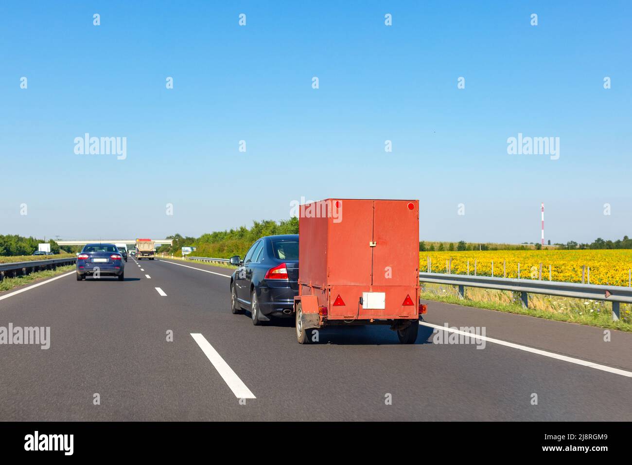 Black car with red carry-on cargo trailer on the highway Stock Photo