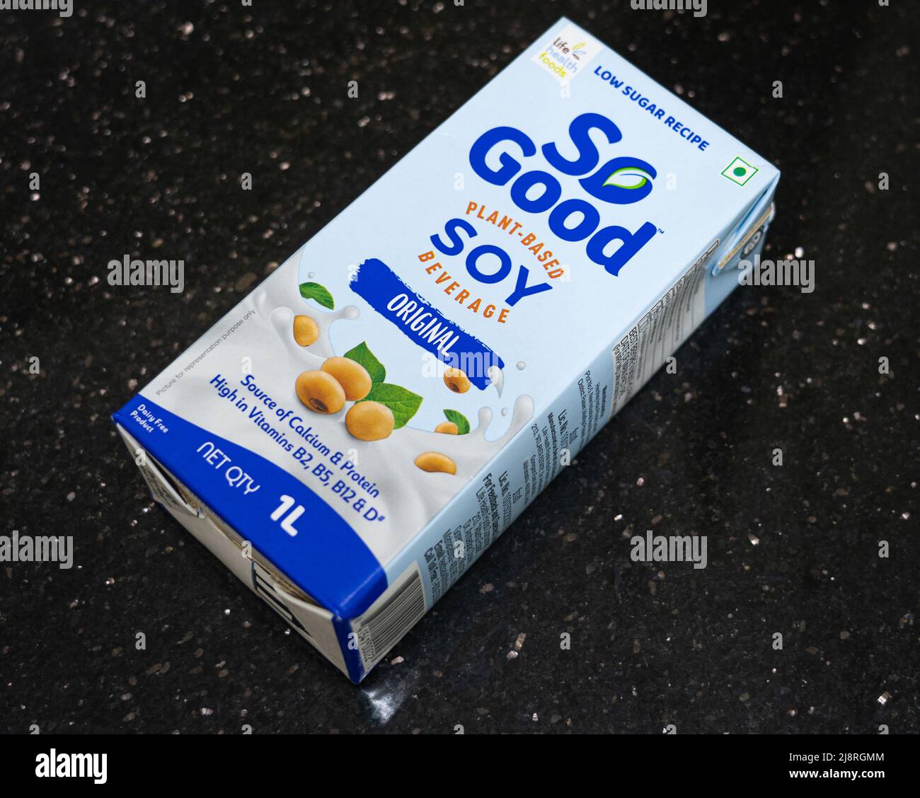 A carton of So Good Soy Milk on a black granite background. Stock Photo