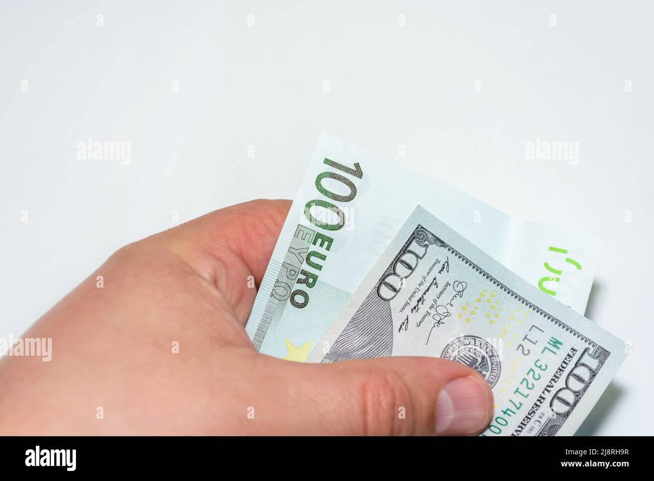 In a man's hand 100 dollars and one hundred euros on a white background. Choice of money. Exchange rates. Stock Photo