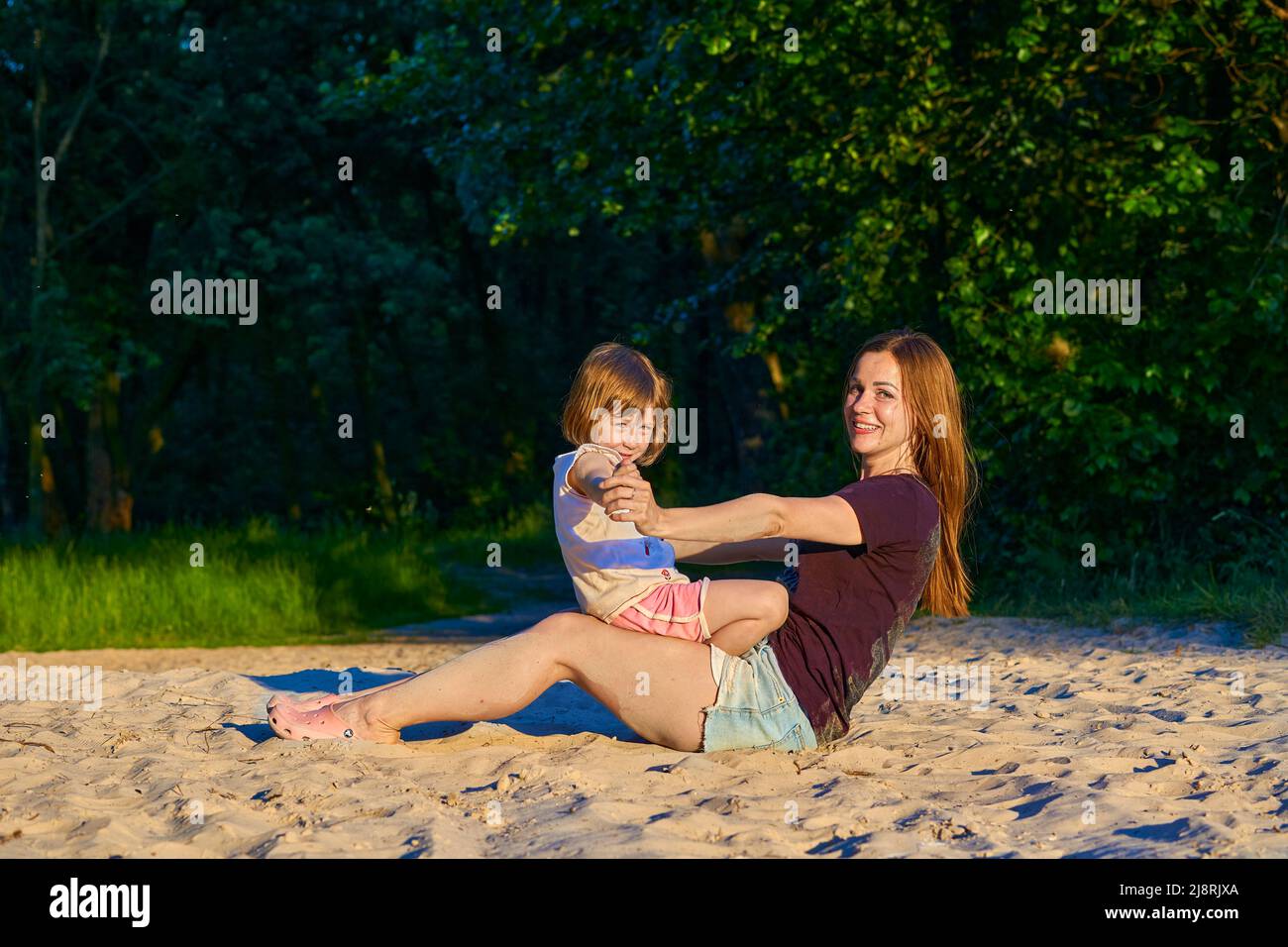 Wonderful cute baby girl child playing with happy mom among greenery sand dunes Stock Photo