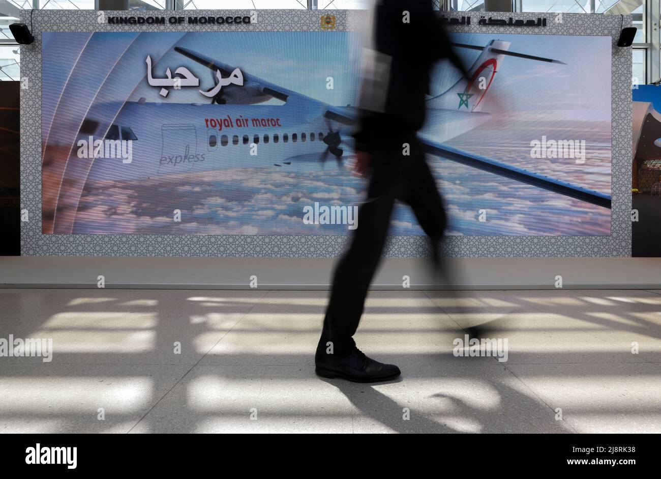 Leipzig, Germany. 18th May, 2022. A visitor to the International Transport Forum walks through the Congress Center Leipzig on a video screen of Morocco. Some 600 experts are expected to attend the three-day International Transport Forum under the presidency of the North African country, including numerous transport ministers from the 63 member states of the OECD's International Transport Forum (ITF). One focus this year should be Ukraine, with its blocked trade routes and infrastructure destroyed in the war. Credit: Jan Woitas/dpa/Alamy Live News Stock Photo