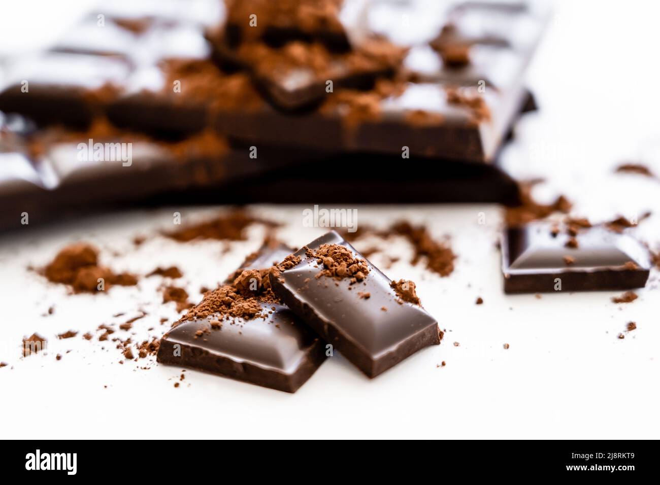 Close up view brown chocolate pieces and cocoa on white background ...
