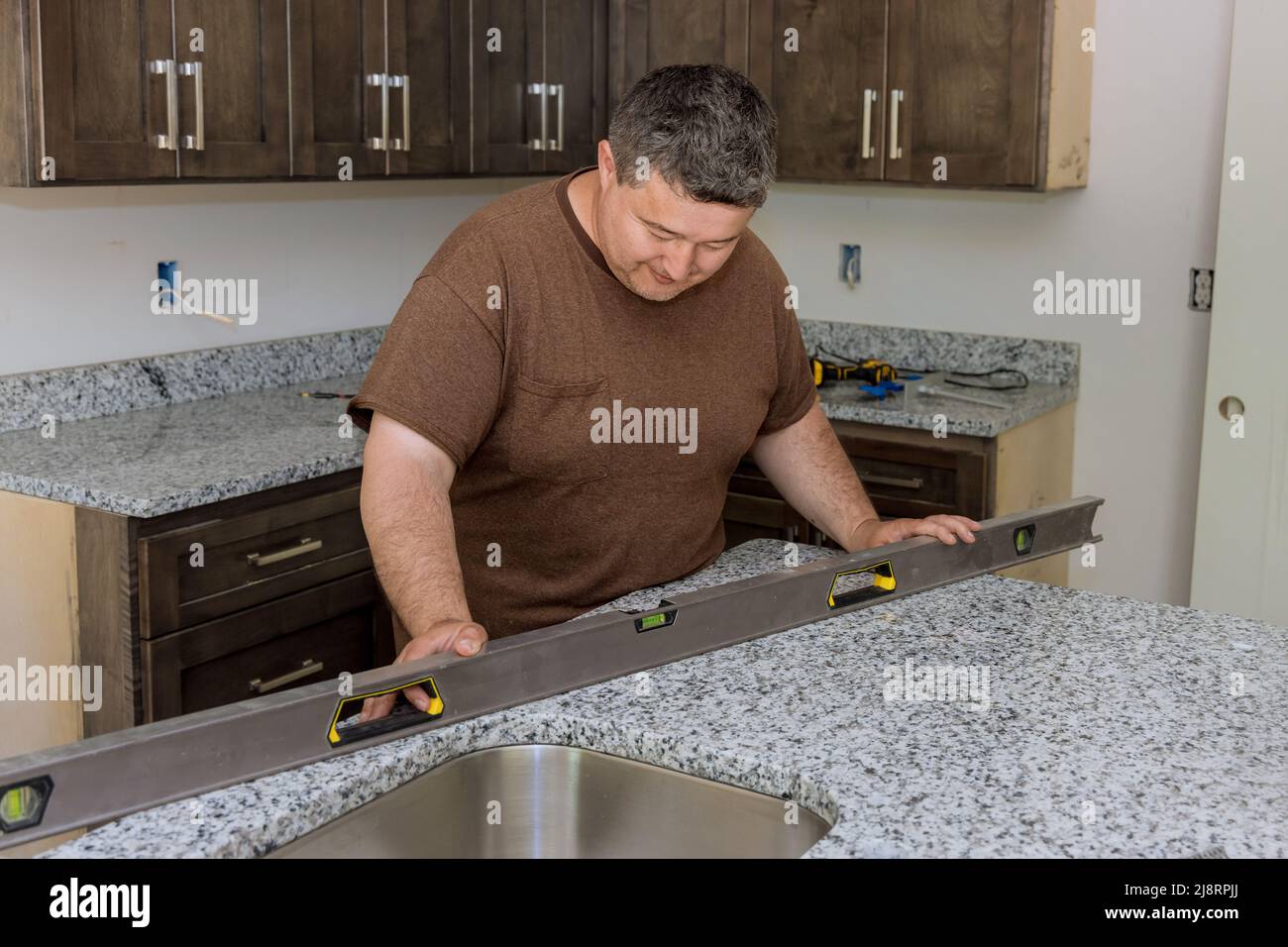 Worker hanging level the leveling countertop for new kitchen Stock