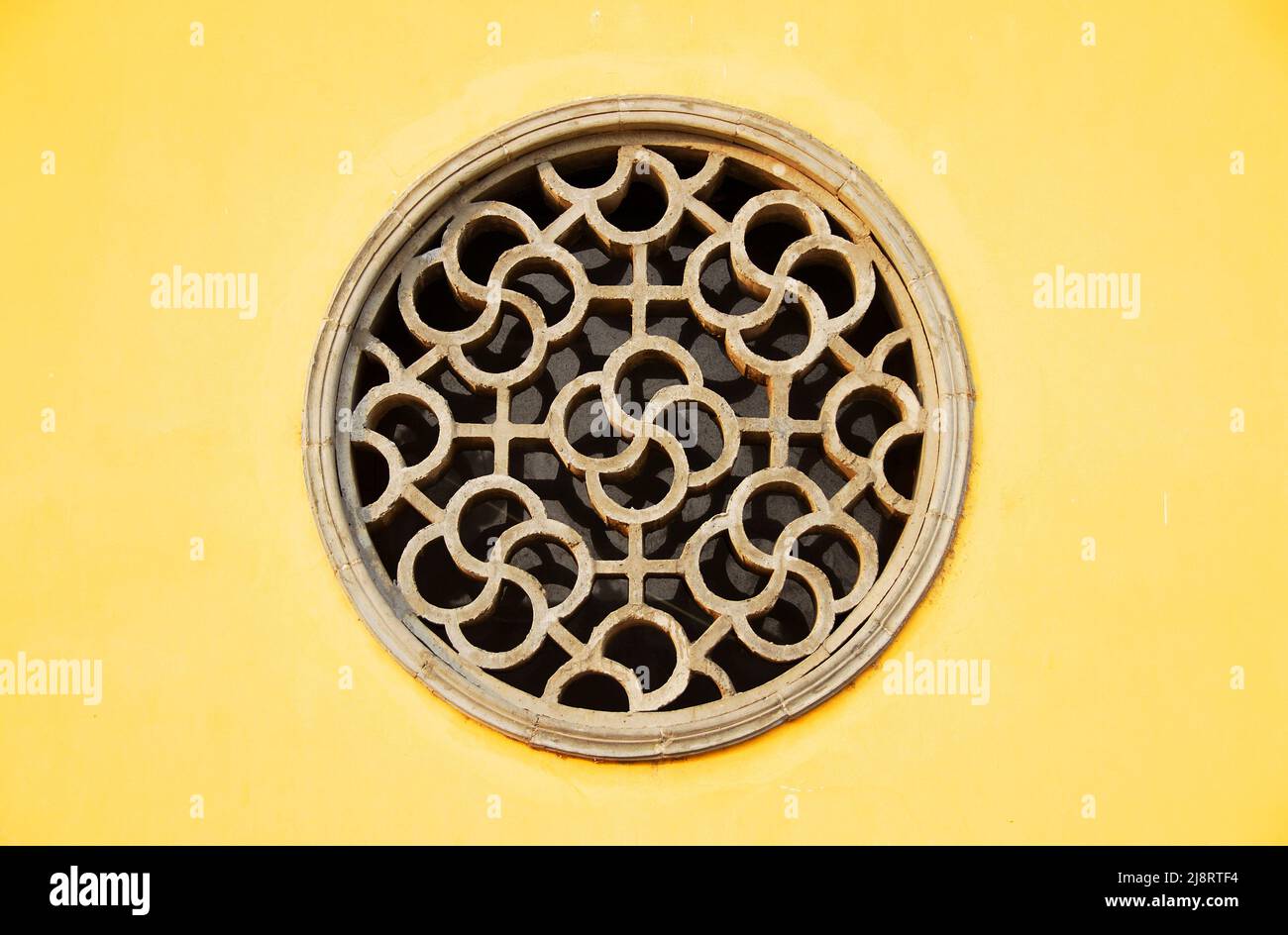 Zhenjiang, Jiangsu Province, China: A circular window set in a yellow wall at Dinghui Temple in Zhenjiang. Stock Photo