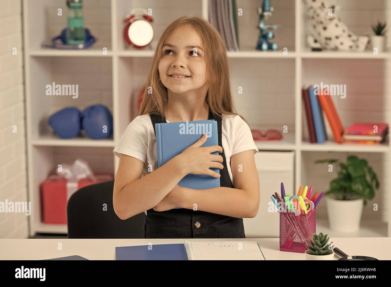 dreamy kid hold book at school lesson in classroom wear uniform