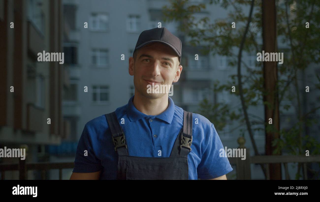 Happy young delivery man courier in wearing the blue hat Stock Photo
