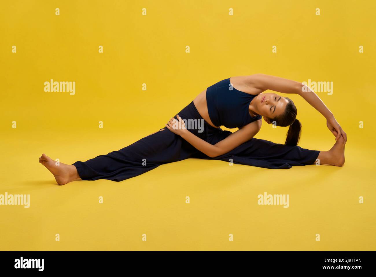 Athletic woman doing a frontal split yoga pose on a white wooden floor in a  high angle view with copyspace in a health and fitness concept Stock Photo  - Alamy
