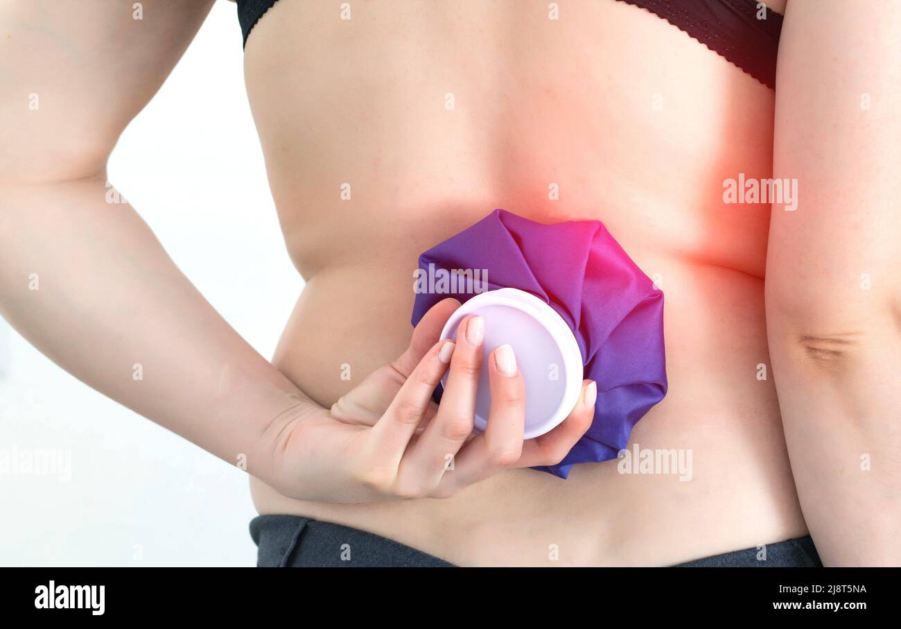 Girl holding a medical ice bag on the back of the spine. Concept for pain relief from muscle spasms and bruising pain Stock Photo