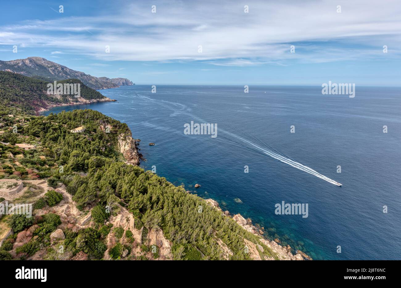 UNESCO World Heritage Site Serra de Tramuntana mountain coastline overlooking speedboat travelling in blue Mediterranean Sea by Banyalbufar viewpoint Stock Photo