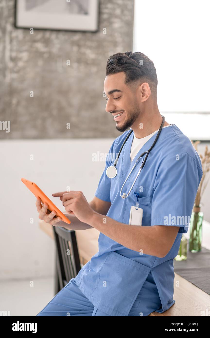 Joyful Caucasian male physician using his gadget Stock Photo