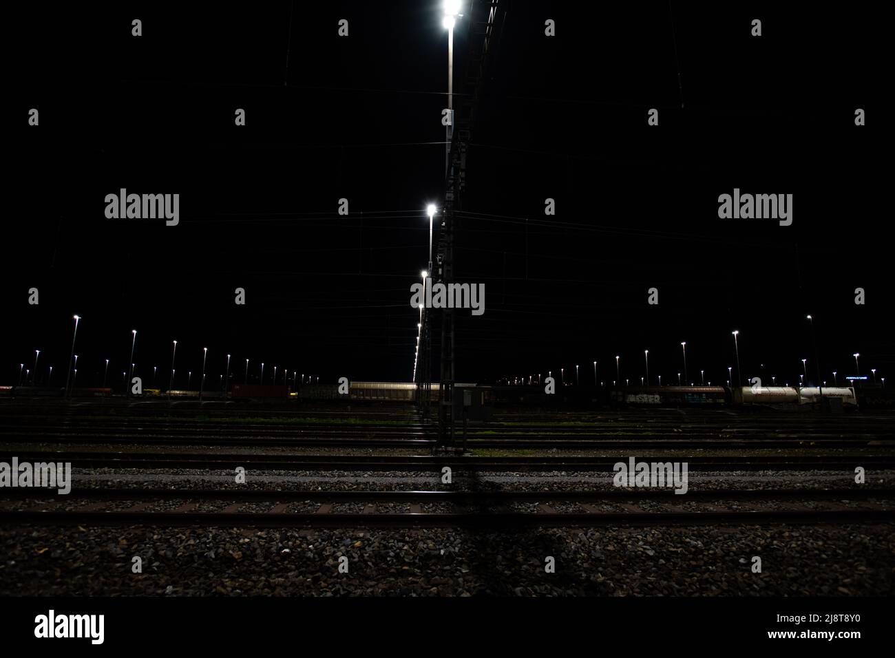 Freight station at night in Zurich, Spreitenbach. Freight trains are illuminated by bright headlights. Image is dark in foreground. Stock Photo