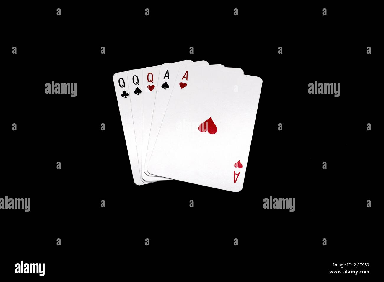 Full House of queens and aces.  Poker hand isolated on black background Stock Photo