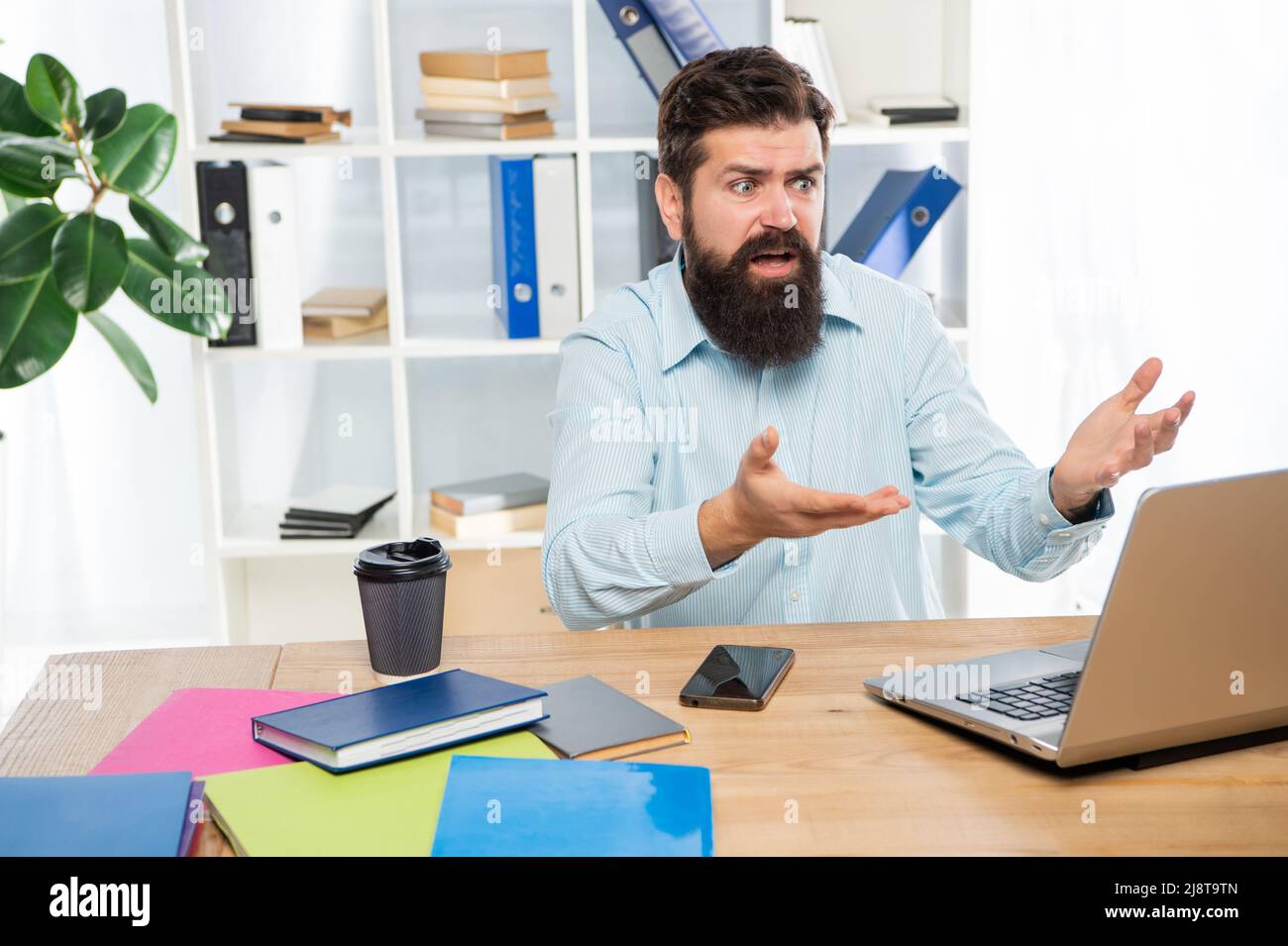 Indignant businessman complaining while working at work computer in office, indignation Stock Photo
