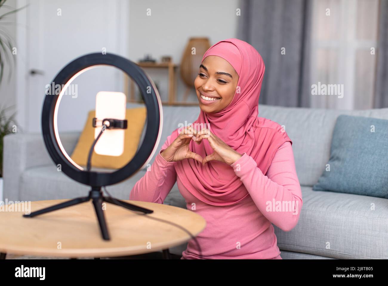 Happy african american female blogger recording video blog on social network, showing the heart symbol with her hands Stock Photo