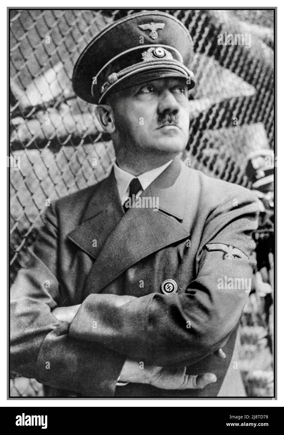 Adolf Hitler pensive serious arms folded. Posing outdoors at the battlefront 1940s WW2 in military uniform with cap, wearing a Nazi Party swastika pin badge Stock Photo