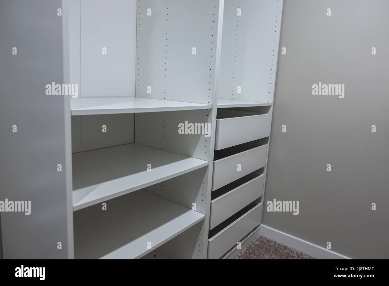 View of tall, white and drawers inside a narrow walk in closet inside a master bedroom